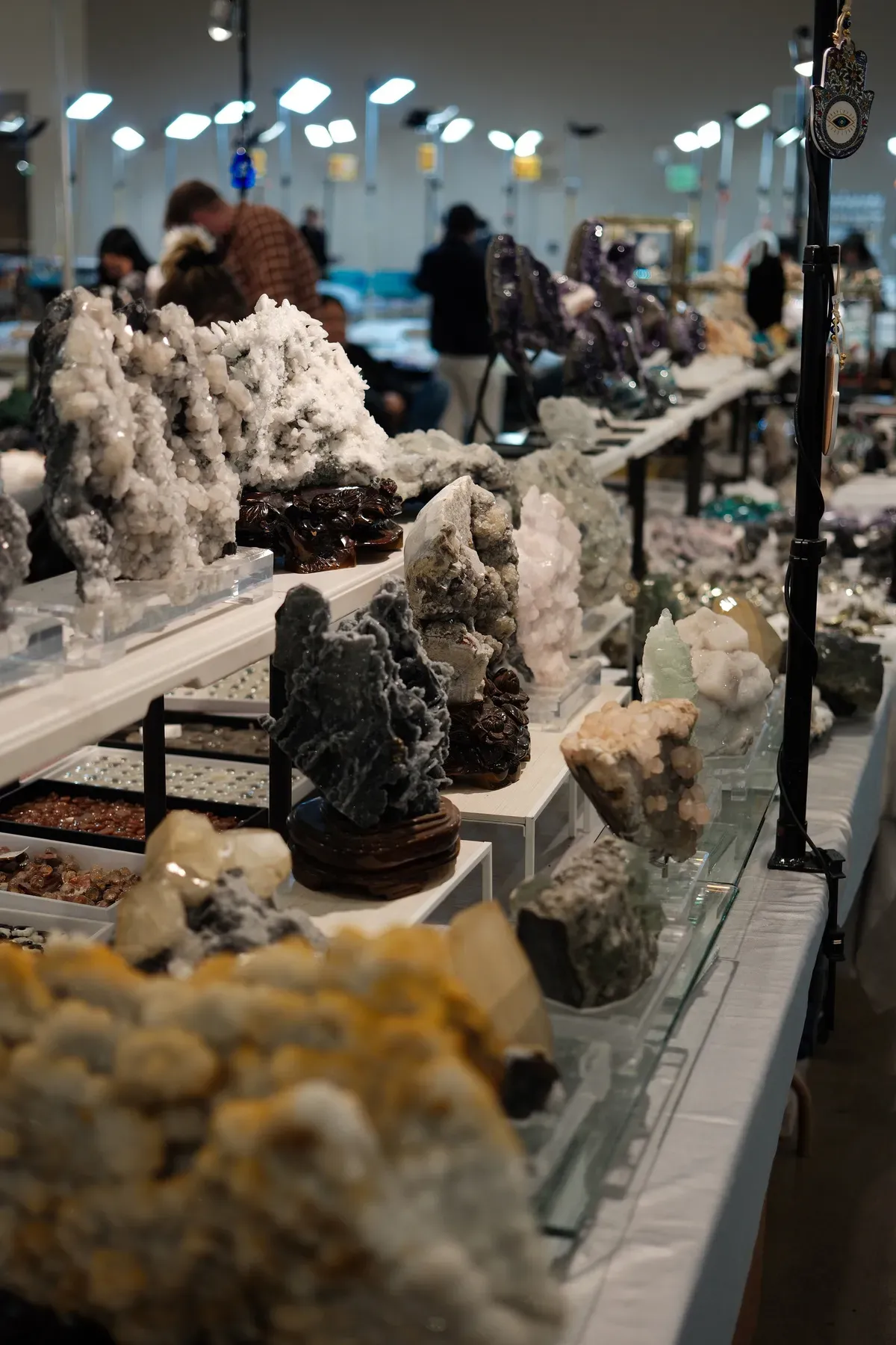 A display table features a variety of mineral and crystal formations at a market or exhibition.