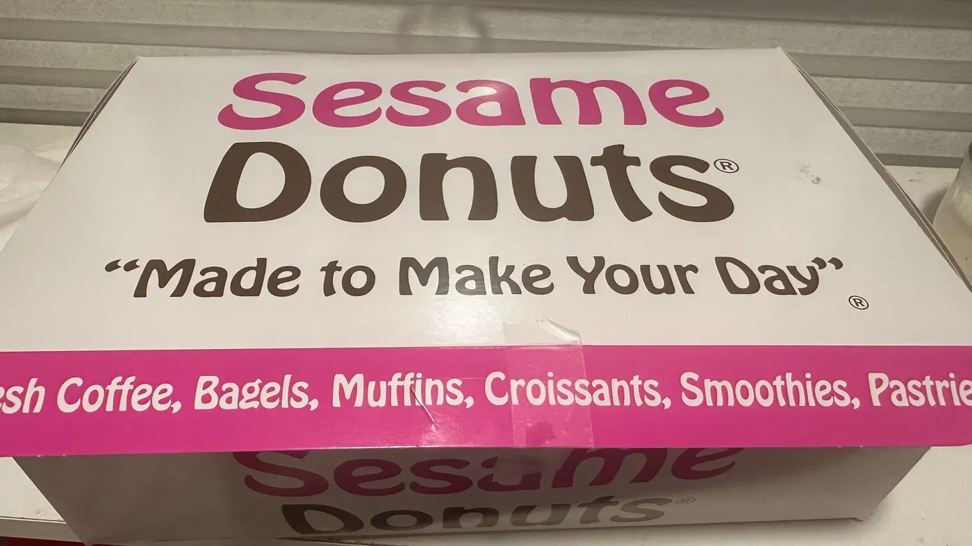 A Sesame Donuts box is displayed with the slogan Made to Make Your Day printed on it.